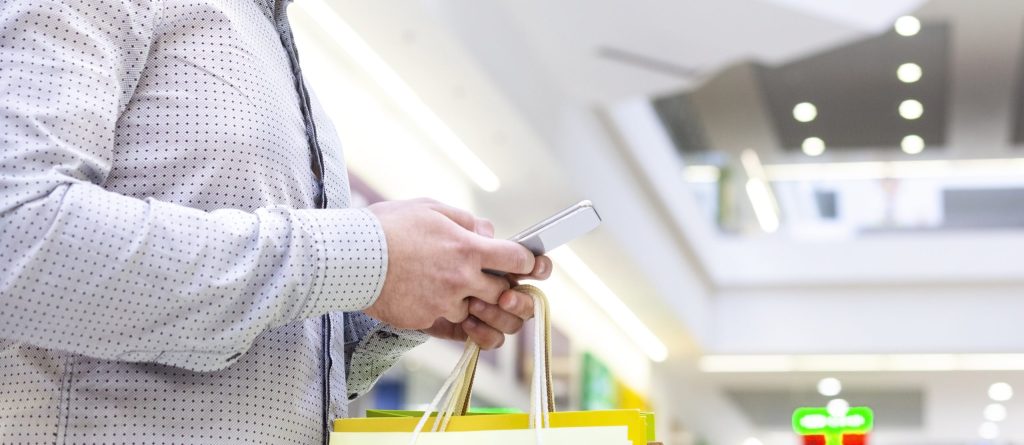 man shopping in mall and using phone copy space HVD7Z6W